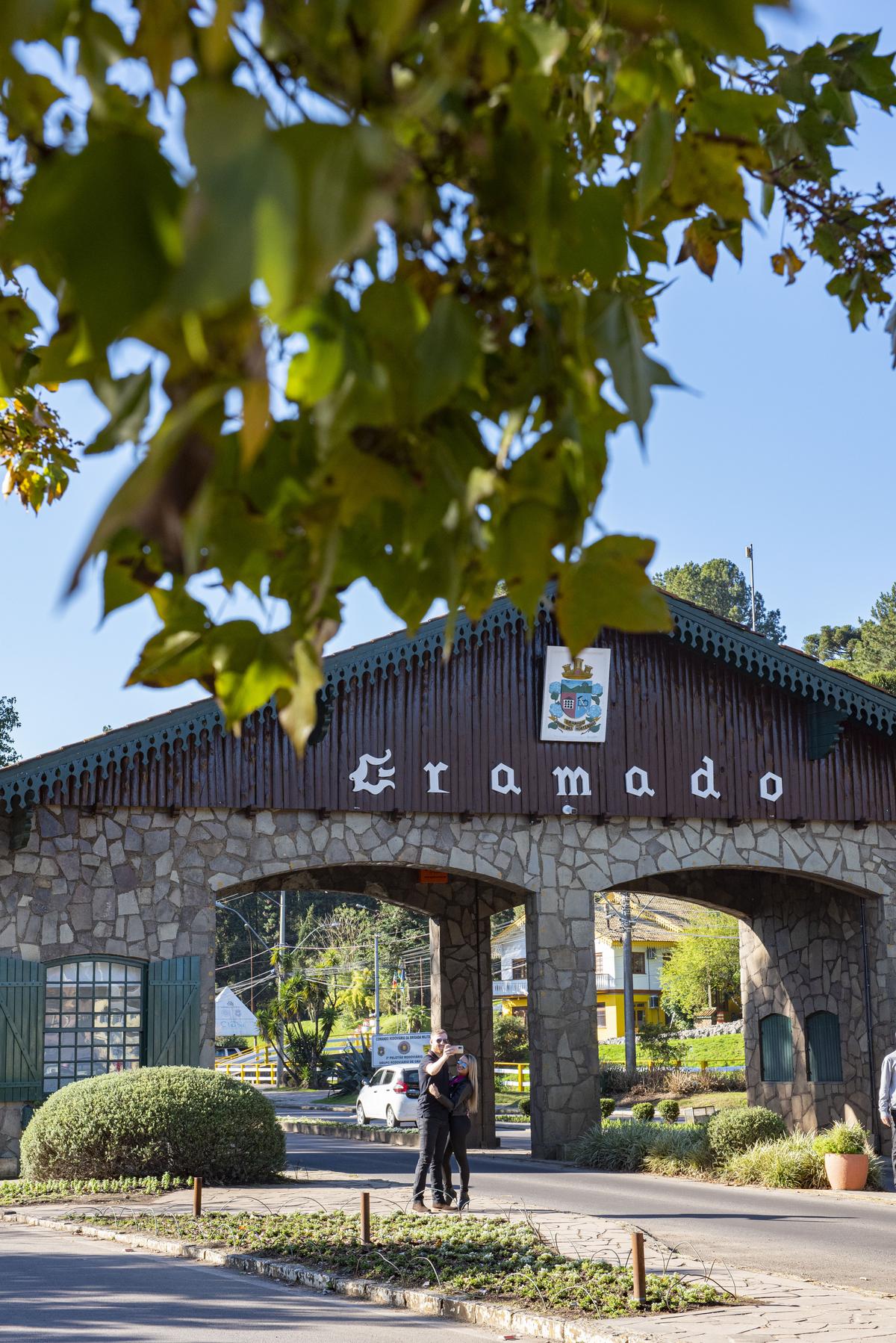 Foto panorâmica de um trem moderno em movimento rumo à cidade de Gramado com a paisagem da serra ao fundo, simbolizando um convite a turistas e investidores.